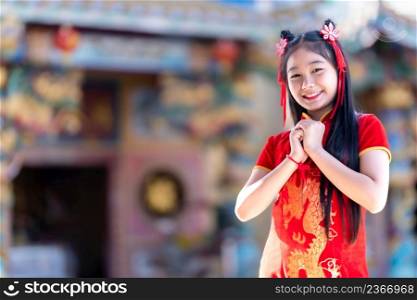 Portrait smiles Cute little Asian girl wearing red cheongsam dress traditional decoration for Chinese new year festival celebrate culture of china at Chinese shrine
