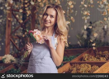 portrait smiling blonde female florist holding flower bouquet hand