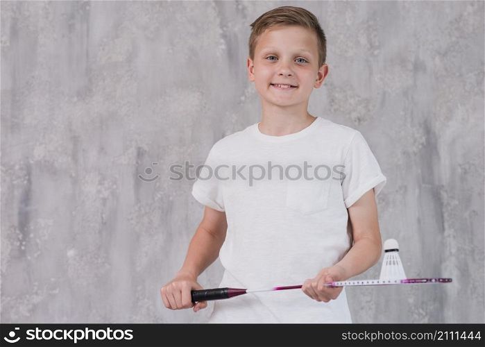 portrait smiling boy holding racket shuttlecock looking camera