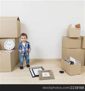 portrait smiling boy standing near cardboard boxes his new house