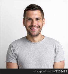 portrait smiling charming young man grey t shirt standing against plain background