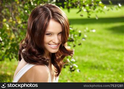 Portrait smiling curly woman in a summer garden
