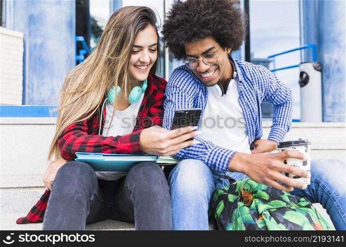 portrait smiling diverse young students looking mobile phone