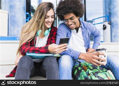 portrait smiling diverse young students looking mobile phone
