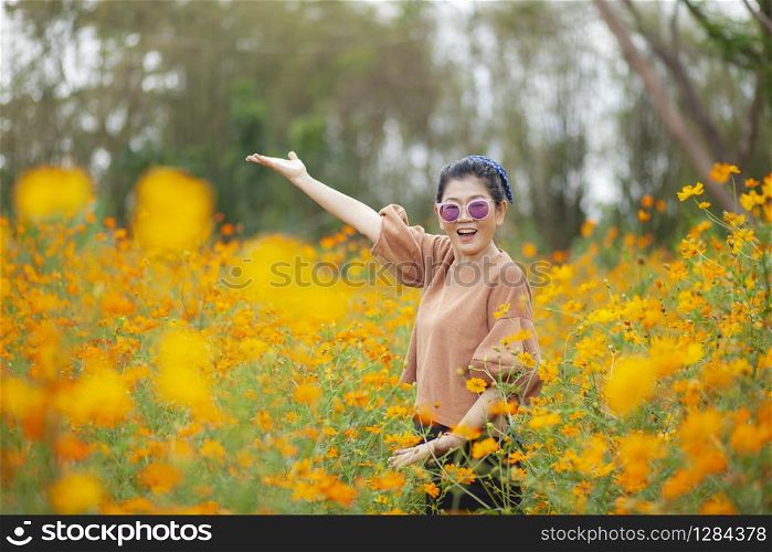 portrait smiling face asian woman standing with happiness emotion in yellow cosmos blooming field