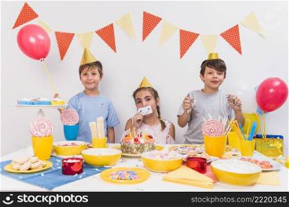 portrait smiling friends holding smiley card balloon confetti with food table