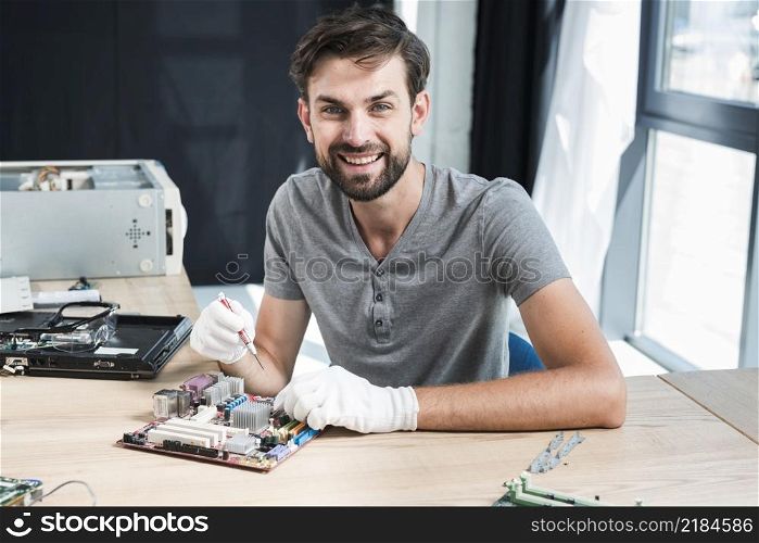 portrait smiling male technician working computer motherboard