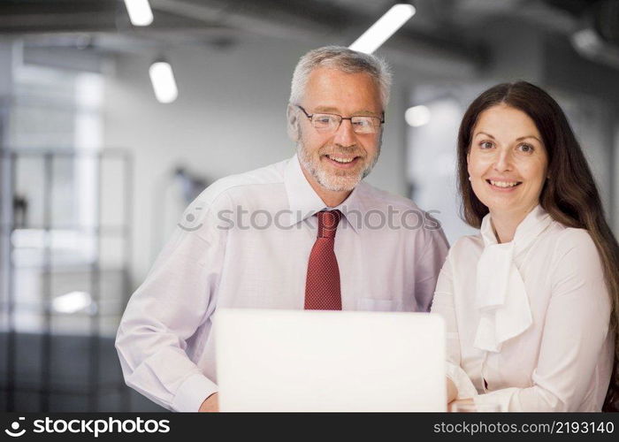 portrait smiling senior businessman businesswoman with laptop office