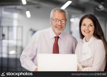 portrait smiling senior businessman businesswoman with laptop office