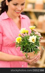 Portrait smiling woman hold yellow potted flowers in garden shop