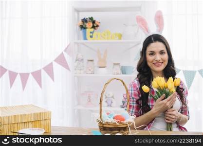portrait smiling woman wearing bunny ears holding tulips hand
