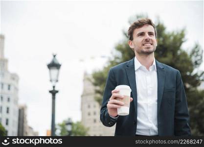portrait smiling young businessman holding takeaway coffee cup hand