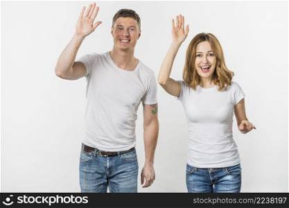portrait smiling young couple waving their hands looking camera