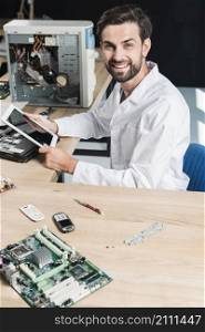 portrait smiling young male technician holding digital tablet
