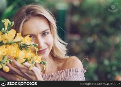 portrait smiling young woman touching yellow sia flowers with care