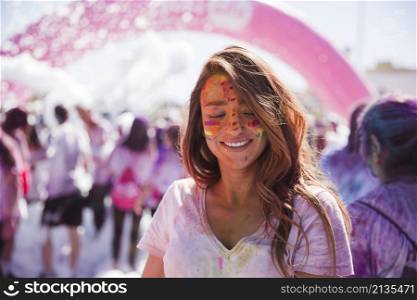portrait smiling young woman with holi color face