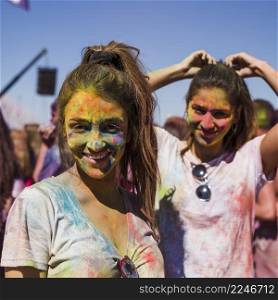 portrait smiling young women with holi colors her face looking camera
