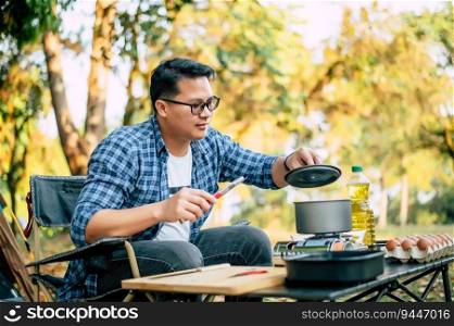 Portrait Thai traveler man glasses pouring sunflower oil into a frying pan. Outdoor cooking, traveling, c&ing, lifestyle concept.
