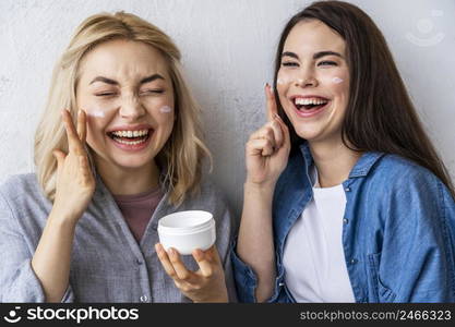 portrait women laughing playing with moisturizer