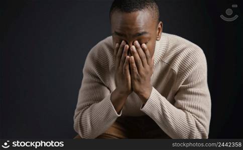 portrait young african man with hands covering face