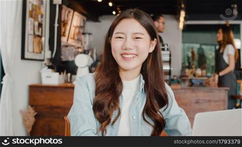 Portrait young Asia freelance lady woking feeling happy at coffee shop. Attractive Japanese businesswoman relax toothy smile looking to camera in urban cafe or restaurant with laptop.