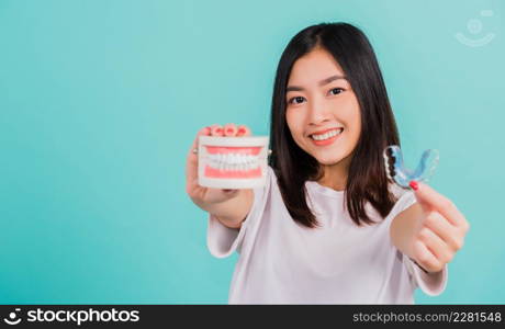 Portrait young Asian beautiful woman smiling holding silicone orthodontic retainers for teeth retaining tools after removable braces, Female hold model teeth before, Orthodontics dental healthy care