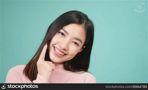 Portrait young Asian beautiful woman smiling wear silicone orthodontic retainers on teeth isolated on blue background, Teeth retaining tools after removable braces. Dental hygiene and health concept