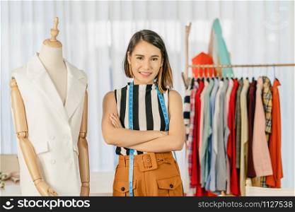 Portrait Young Asian designer woman are arms crossed at workplace beside Clothes mannequins, small business startup, Business owner entrepreneur, modern freelance job lifestyle concept.asean people