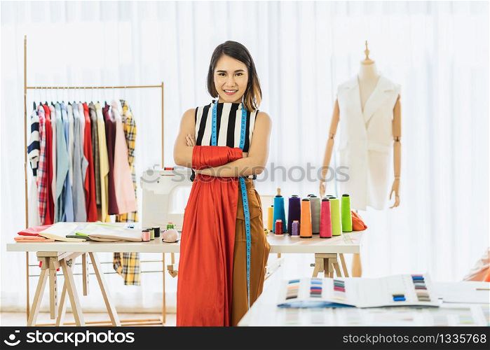 Portrait Young Asian Designer woman are arms crossed at workplace over Clothes mannequins, small business startup, Business owner entrepreneur, modern freelance job lifestyle concept.asean people