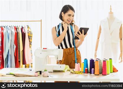 Portrait Young Asian Designer woman working and using the technology tablet at workplace over Clothes mannequins, small business startup, Business owner entrepreneur, modern freelance job lifestyle concept.asean people