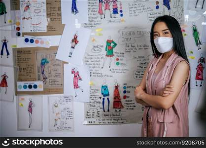 Portrait young asian female standing in modern atelier. Positive woman creative worker wearing medical face mask in studio. distance and new normal concept
