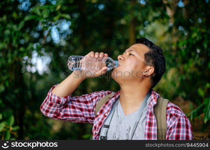 Portrait young Asian trekking drink water from plastic bottle during break on forest trail, copy space