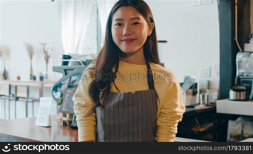 Portrait young Asian woman barista feeling happy smiling at urban cafe. Small business owner Korean girl in apron relax toothy smile looking to camera standing at the counter in coffee shop.