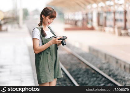 Portrait Young asian woman smiling tourist Trave≤r girl walking and with a holding the camera waits train travel jour≠y is taken in railway platform Thailand,∑mer relax vacation Concept.