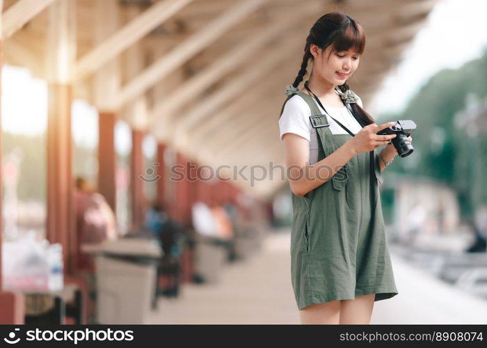 Portrait Young asian woman smiling tourist Traveler girl walking and with a holding the camera waits train travel journey is taken in railway platform Thailand, summer relax vacation Concept.