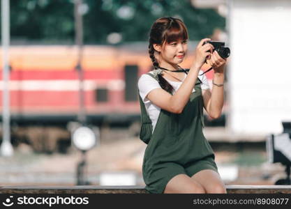 Portrait Young asian woman smiling tourist Traveler girl walking and with a holding the camera waits train travel journey is taken in railway platform Thailand, summer relax vacation Concept.