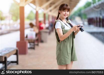 Portrait Young asian woman smiling tourist Traveler girl walking and with a holding the camera waits train travel journey is taken in railway platform Thailand, summer relax vacation Concept.