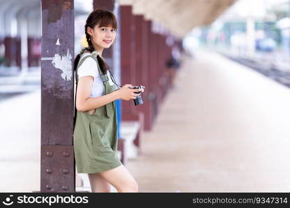 Portrait Young asian woman smiling tourist Traveler girl walking and with a holding the camera waits train travel journey is taken in railway platform Thailand, summer relax vacation Concept.