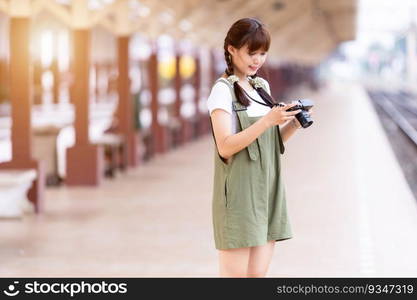 Portrait Young asian woman smiling tourist Traveler girl walking and with a holding the camera waits train travel journey is taken in railway platform Thailand, summer relax vacation Concept.