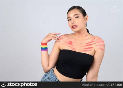 Portrait young asian woman with red lipstick mark on her face and body in sexy clothing with Multi-colored wristbands on her wrist in concept LGBQ on white background