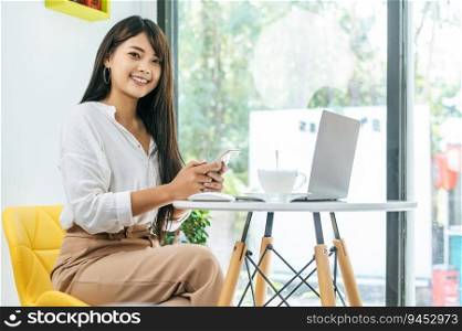 Portrait Young Asian working woman holding smartphone working on laptop computer at coffee shop, working with technology device online communication, business concept