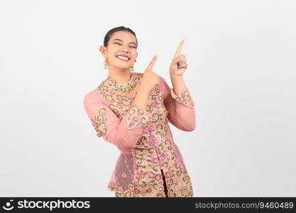 Portrait Young beautiful woman dress up in local culture in southern region with charming gesture smile and point finger on two hands out on copy space of white background