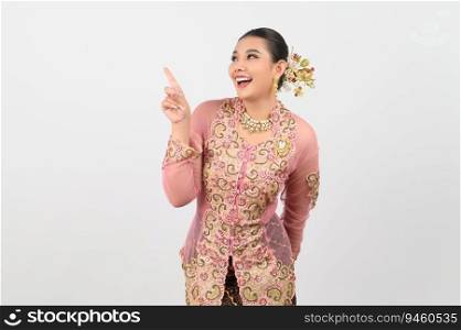 Portrait Young beautiful woman dress up in local culture in southern region with charming gesture smile and point finger  out on white background, copy space