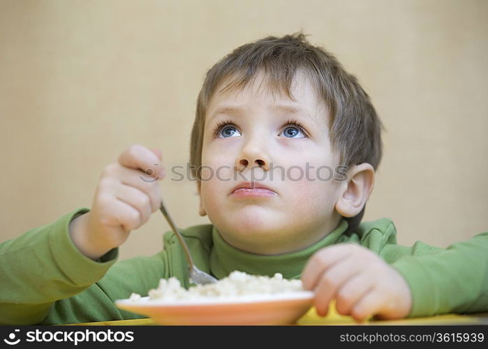 Portrait young boy gazing upwards while eating