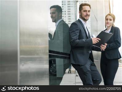 portrait young businessman holding folder hand standing with her female s colleague outdoors
