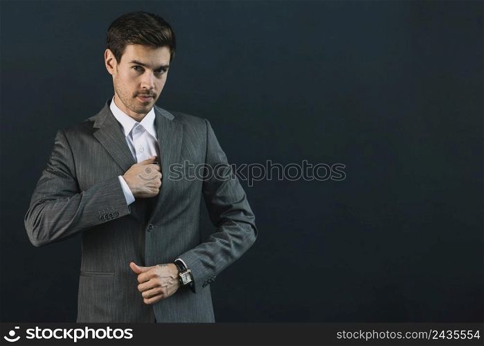 portrait young businessman suit standing against black background