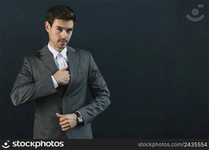 portrait young businessman suit standing against black background