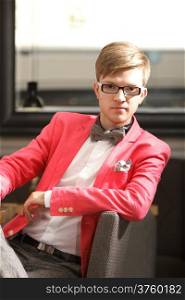 Portrait young handsome stylish man fashion model in glasses wearing bright red jacket and bow tie posing indoor
