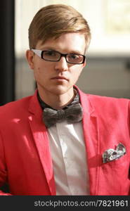 Portrait young handsome stylish man fashion model in glasses wearning bright red jacket and bow tie posing indoor