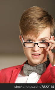 Portrait young handsome stylish man fashion model in glasses wearning bright red jacket and bow tie posing indoor